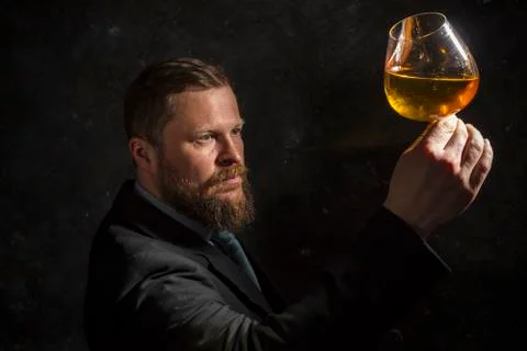 Solid confident bearded man in suit with glass of whisky Stock Photos