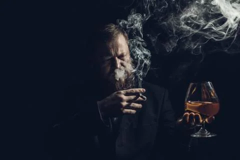 Solid confident bearded man in suit with glass of whisky and cigar with fume Stock Photos