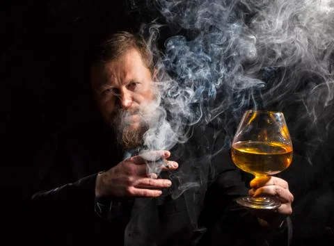 Solid confident bearded man in suit with glass of whisky and cigar with fume Stock Photos
