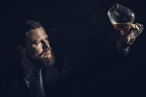 Solid confident bearded man in suit with glass of whisky Stock Photos