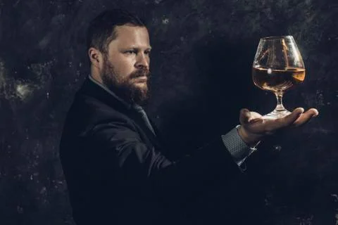 Solid confident bearded man in suit with glass of whisky Stock Photos