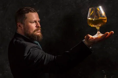 Solid confident bearded man in suit with glass of whisky Stock Photos