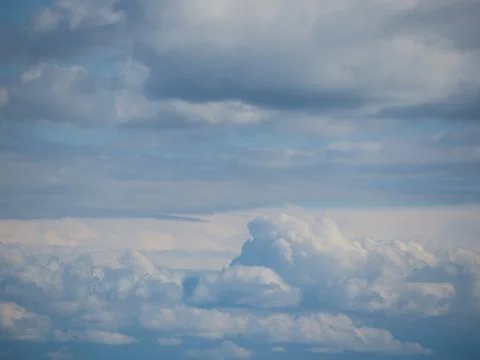 Solid cumulus clouds at eye level in a blue sky. Natural sky background or wa Stock Photos