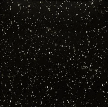 Solid dark glass filled with air bubbles and light as background Foto stock