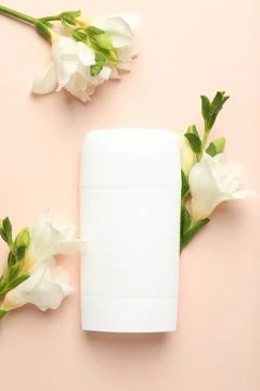 Solid deodorant and beautiful eustoma flowers on beige background, flat lay Stockfoto's