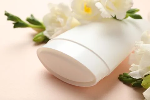 Solid deodorant and beautiful eustoma flowers on beige background, closeup Stock Photos