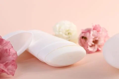 Solid deodorant and beautiful eustoma flowers on beige background, closeup 스톡 사진