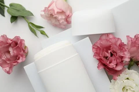 Solid deodorant and beautiful eustoma flowers on white background, top view 스톡 사진