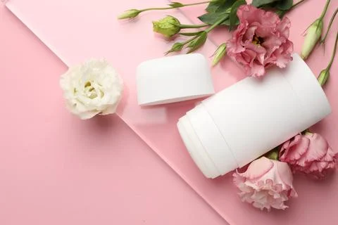 Solid deodorant and beautiful eustoma flowers on pink background, top view 스톡 사진