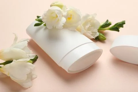 Solid deodorant and beautiful eustoma flowers on beige background, closeup 스톡 사진