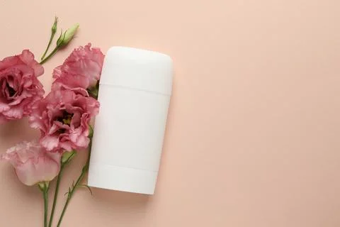 Solid deodorant and beautiful eustoma flowers on beige background, flat lay.. 스톡 사진