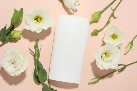 Solid deodorant and beautiful eustoma flowers on beige background, flat lay Stock Photos