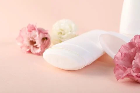 Solid deodorant and beautiful eustoma flowers on beige background, closeup 스톡 사진