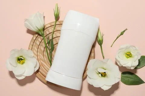 Solid deodorant and beautiful eustoma flowers on beige background, flat lay Stock Photos