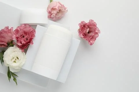 Solid deodorant and beautiful eustoma flowers on white background, top view Stock Photos