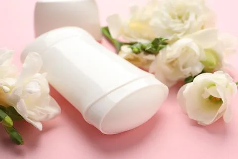 Solid deodorant and beautiful eustoma flowers on pink background, closeup Stock Photos