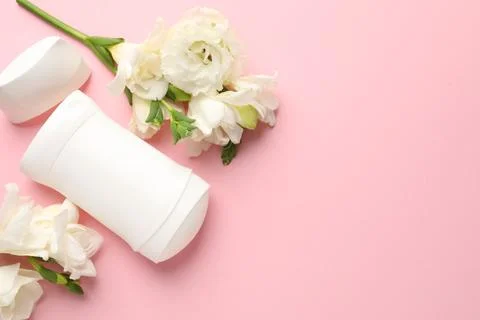 Solid deodorant and beautiful eustoma flowers on pink background, flat lay... Stock Photos