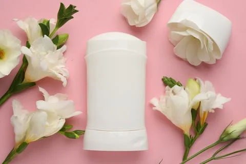 Solid deodorant and beautiful eustoma flowers on pink background, flat lay Stock Photos