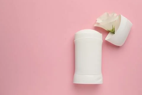 Solid deodorant and beautiful eustoma flower on pink background, top view. .. Stock Photos