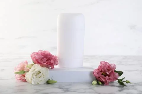Solid deodorant and beautiful eustoma flowers on white marble table Stock Photos