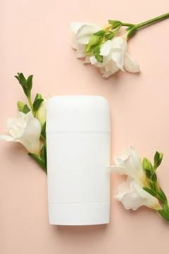 Solid deodorant and beautiful eustoma flowers on beige background, flat lay Stock Photos