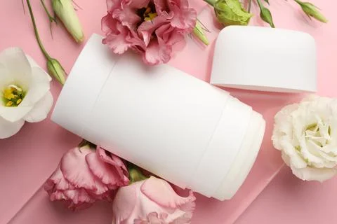 Solid deodorant and beautiful eustoma flowers on pink background, top view Stock Photos