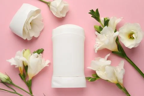 Solid deodorant and beautiful eustoma flowers on pink background, flat lay Stock Photos