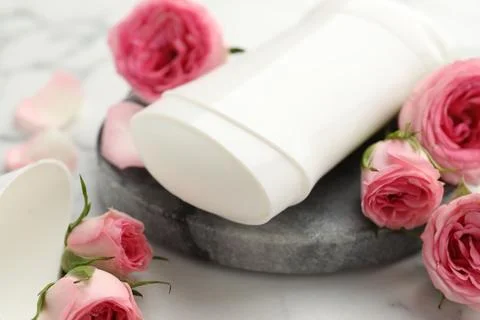 Solid deodorant and beautiful rose flowers on table, closeup 스톡 사진