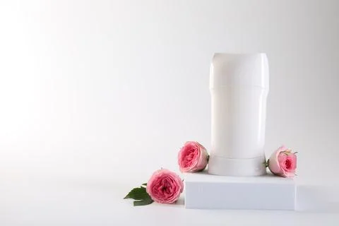 Solid deodorant and beautiful rose flowers on white background, space for tex Stock Photos