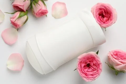 Solid deodorant and beautiful rose flowers on white background, flat lay Stock Photos