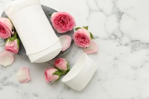 Solid deodorant and beautiful rose flowers on white marble table, flat lay... Stock Photos