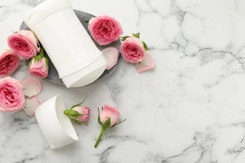 Solid deodorant and beautiful rose flowers on white marble table, flat lay... Stock Photos