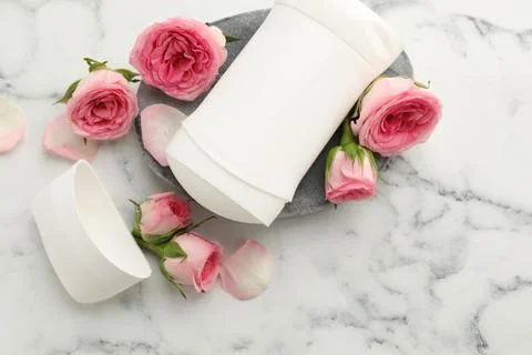 Solid deodorant and beautiful rose flowers on white marble table, top view Stock Photos