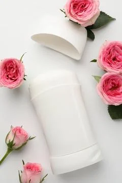 Solid deodorant and beautiful rose flowers on white background, flat lay Stock Photos