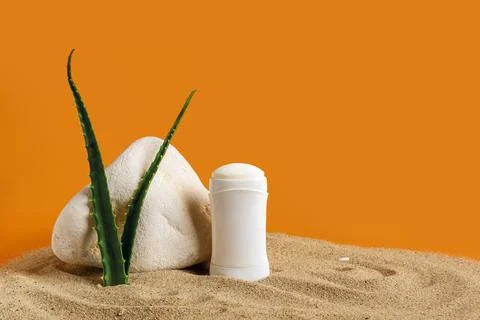 Solid deodorant antiperspirant and aloe green leaves near stone on a sea sand 스톡 사진