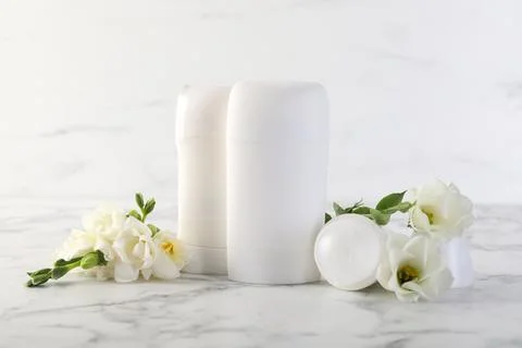 Solid deodorants and beautiful eustoma flowers on white marble table Stock Photos