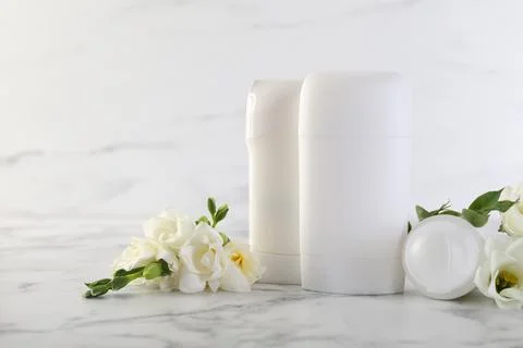 Solid deodorants and beautiful eustoma flowers on white marble table Stock Photos