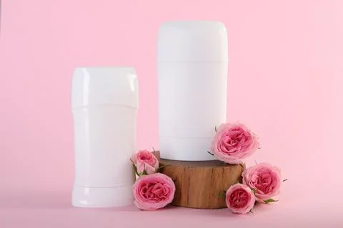 Solid deodorants and beautiful rose flowers on pink background Stock Photos