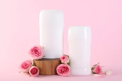 Solid deodorants and beautiful rose flowers on pink background Stock Photos