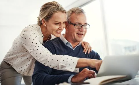 Solid financial planning pays off. a mature couple using a laptop while going Fotos de archivo