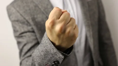 Solid man in gray jacket on white background pulling fist up. threat gesture Stock Footage 114186765