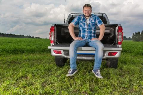 Solid man sitting on car trunk on natural background Stock Photos