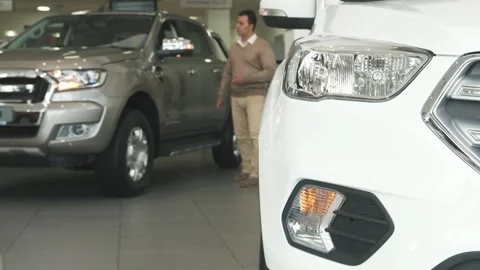 A solid man walks among gleaming cars at the bustling car dealership Stock Footage 311183087
