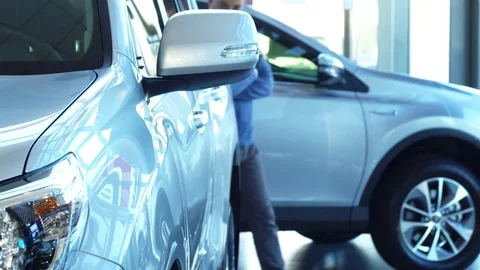 A solid man walks through the automobile showroom and looks at the car Stock Footage 82828858