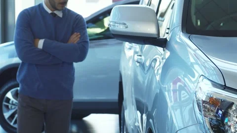 A solid man walks through the automobile showroom and looks at the car Stock-Footage 311942425