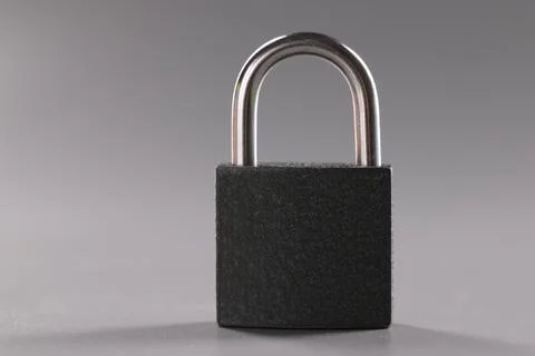 Solid metal locked padlock on grey background, thing to protect home or Foto stock