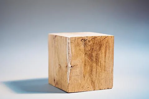 Solid oak cube on a gray background. Very shallow depth of field Stock Photos