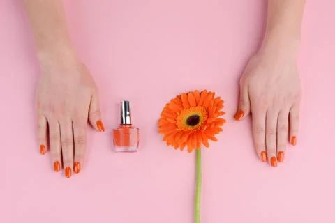 Solid orange nails and flower on pink table Stock Photos