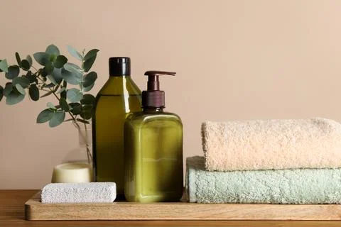 Solid shampoo bar and bottles of cosmetic product on wooden table near beig.. 스톡 사진