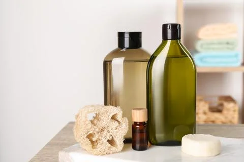 Solid shampoo bar and bottles of cosmetic product on wooden table in bathro.. 스톡 사진